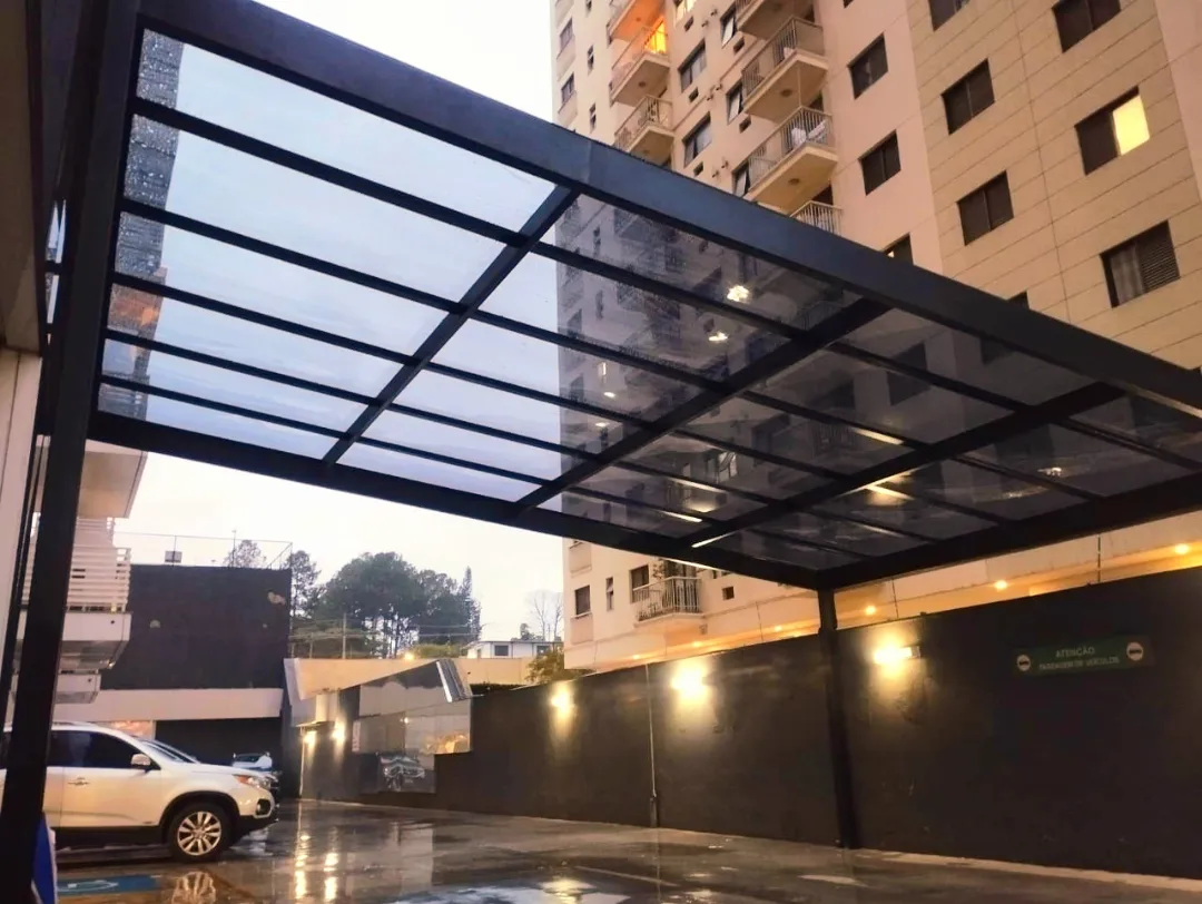 Cobertura de vidro com estrutura preta sobre vaga de garagem